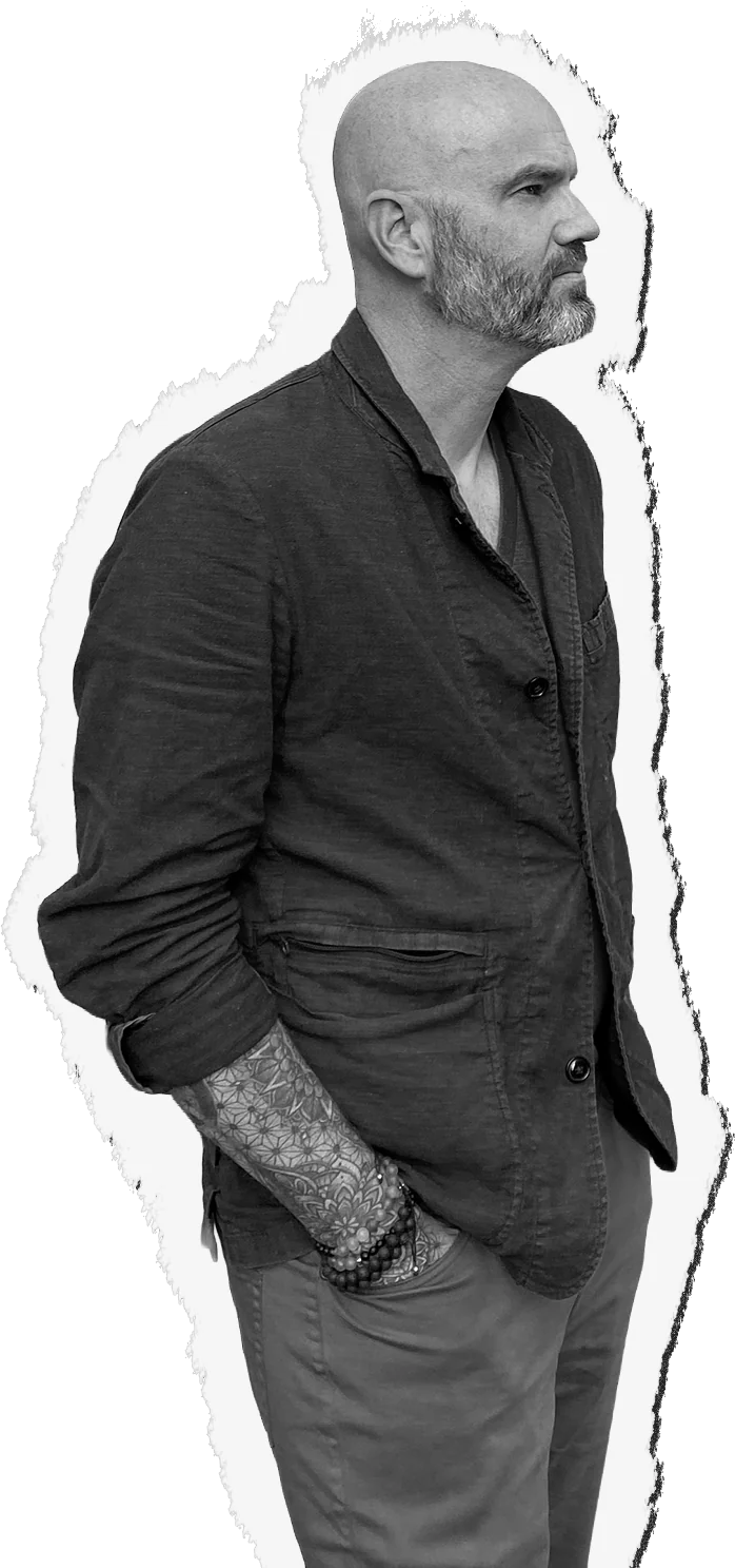 Chad Mullins in profile, hands in his pockets, looking toward the headline