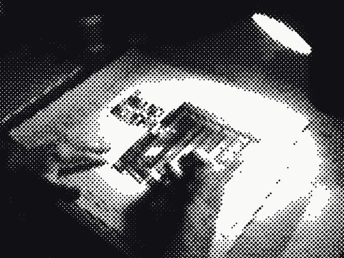 A hand drafting The Brand Blueprint document at a desk under a single lamp, annotated plans spread around it